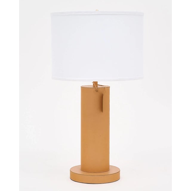 Pair of table lamps wrapped in tan leather and featuring contrasting stitching. They are tagged with a leather stamp...