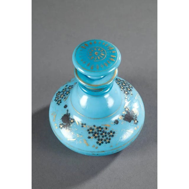 Turquoise blue opaline flask and its flattened stopper that is decorated with a radiant pattern. Gold stripes decorate the...
