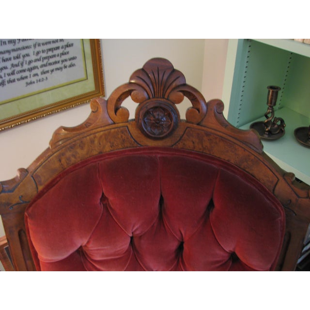 A striking late 19th-century American Victorian armchair showcasing the richly carved walnut craftsmanship and dramatic...