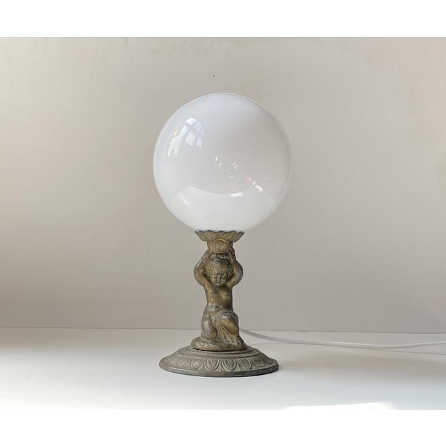 Small unusual table light composed of an Italian Putti in patented bronze supporting a white opaline glass sphere - Globe....
