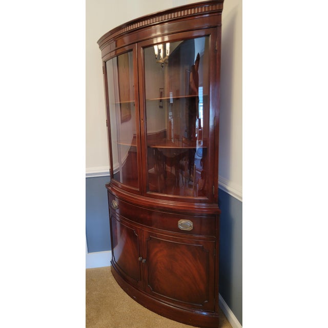 Gorgeous flame mahogany bow front corner cabinet with large glass doors, a locking center drawer with key, and spacious...
