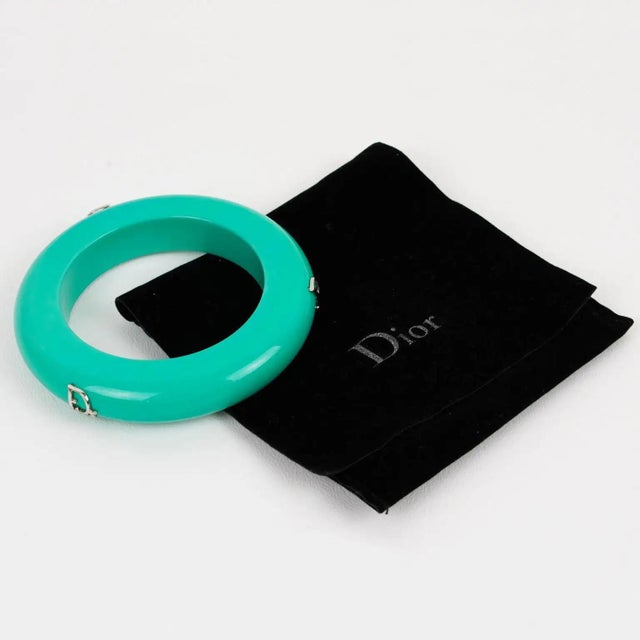 This exquisite Christian Dior bangle bracelet features a stunning turquoise hue and three striking silver "Dior" logos. It...