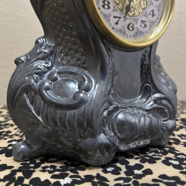 This vintage-inspired mantel clock features an ornate, Rococo-style case with intricate scrollwork and leaf motifs.