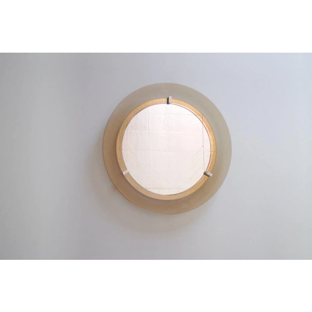 Veca wall mirror composed of deeply inset mirrored glass attached to an enameled metal base and mounted via three chrome...
