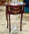 This elegant French style accent table features a rich mahogany-toned finish enhanced by hand-painted decorative artwork...