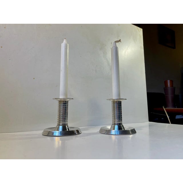 A pair of silver plated candle holders for regular sized candles. Characteristic architectural art deco details with the...