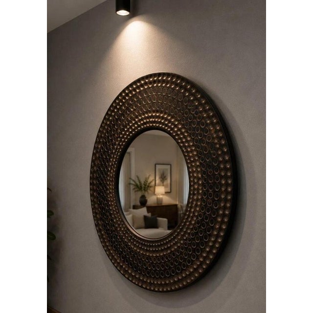 A striking contemporary round wall mirror featuring a richly textured bronze-effect frame with an attractive repeating...