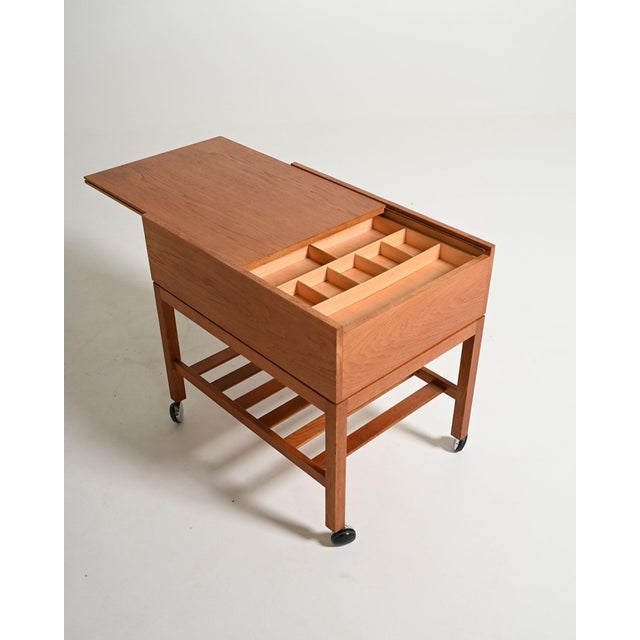 Teak trolley with sliding top, storage compartment, and slatted lower shelf. Danish production, 1960s/1970s. Made in...