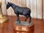 A bronze of a horse titled "Cody — Long Winter, Short Grass" by Tara Brice, the horse walking with head lowered and one...
