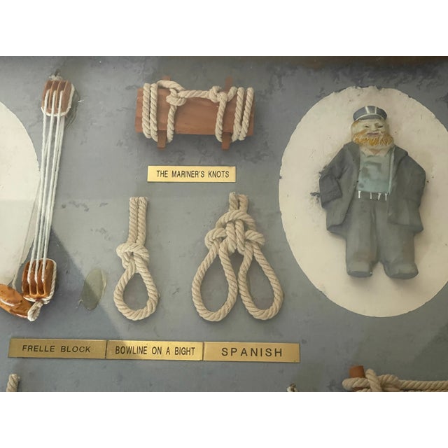 Vintage nautical marine knotted and blocks samples with whimsical sailors figurines, in a shadow box frame.
