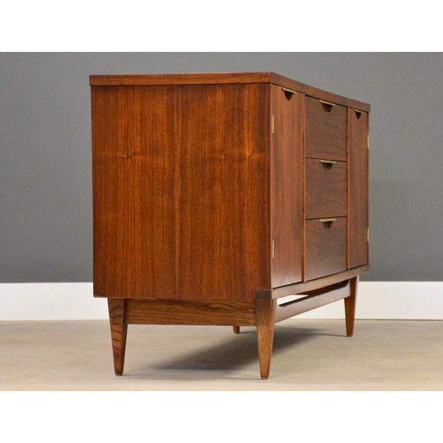 A mid century modern walnut three drawer two door credenza with light brass hardware made by Kent Coffey Tableau. Made in...