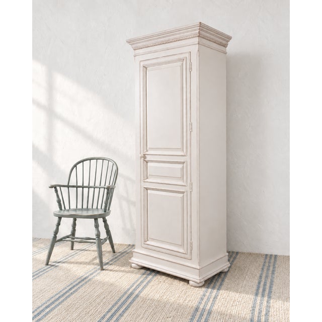 A charming single-door lacquered wood bonnetière or storage cabinet crafted in a Country French Provincial style. The...