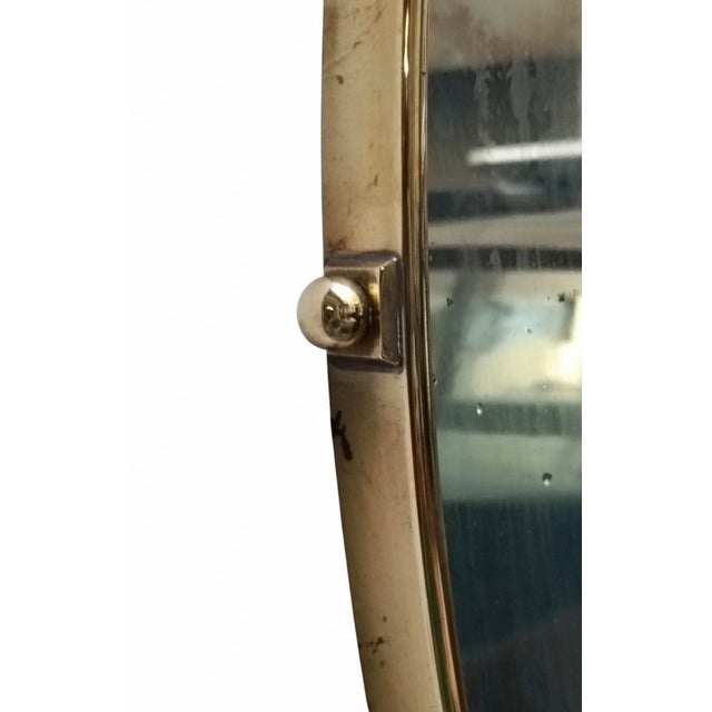 Wall-mounted mirror with a brass frame, dating from around the 1950s. This shape is rare in this style of mirror. It is in...