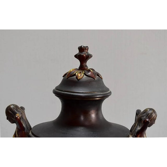 Art Nouveau pendulum in the shape of a Regulate Vase. Two naked young women, covered with their hair, act as handles. The...