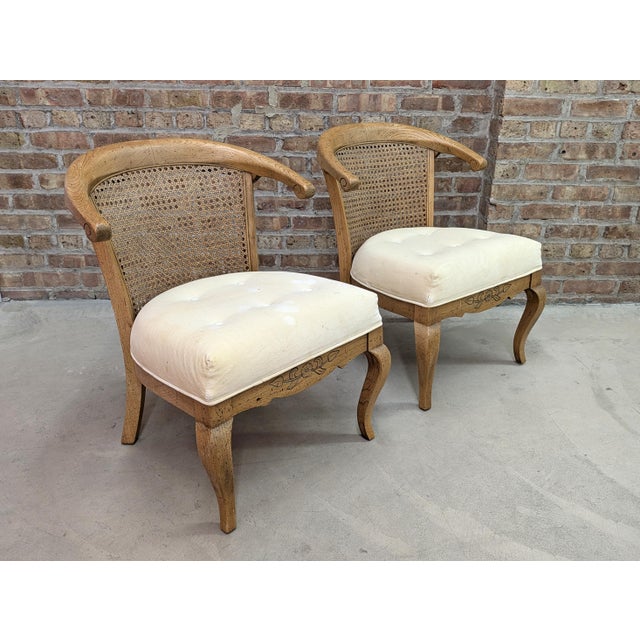 A pair of Late 20th Century French Country armless lounge chairs. The chairs have a casual elegance with French inspired...