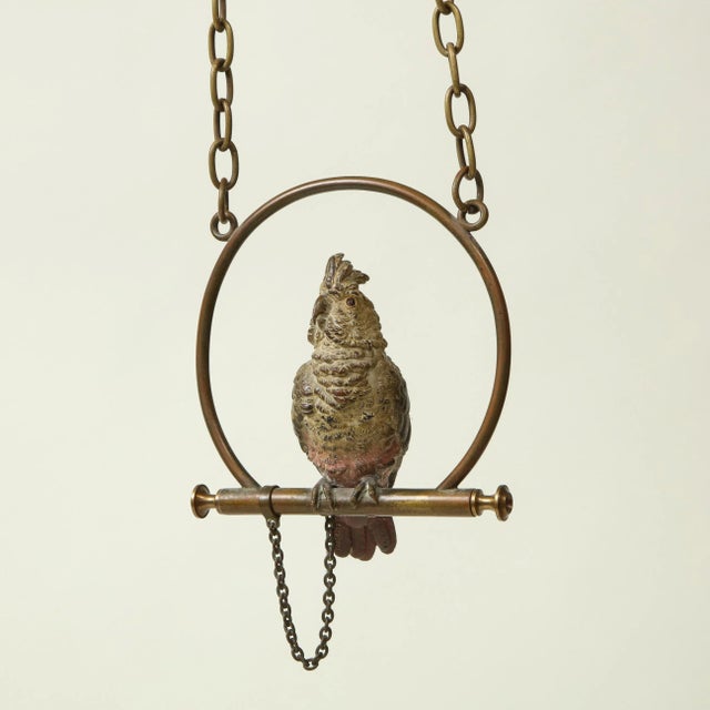 With white, blue, and red plumage; chained to metal perch. Provenance: From the Collection of Mario Buatta, New York, NY