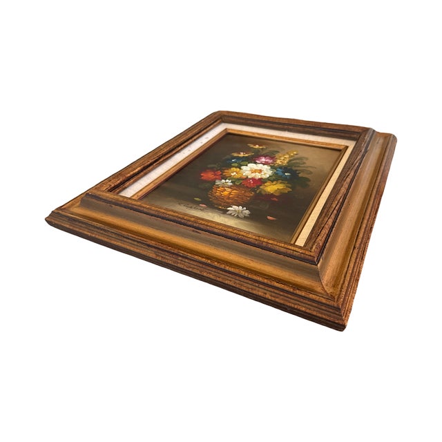 A charming piece of vintage signed factory art depicting a colorful basket overflowing with flowers against a dark...