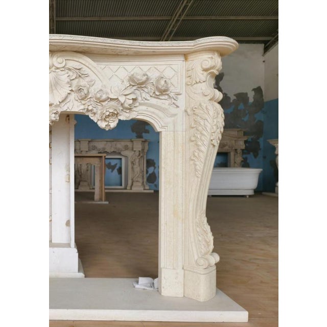 Bursting with theatrical charm and organic elegance, this French Rococo-style fireplace mantle is a masterwork of hand-...
