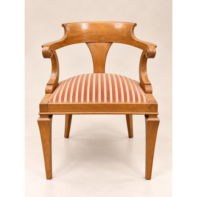 A set of twelve empire/neoclassical style armchairs in solid oak, displaying a golden honey patina from age. the curved,...