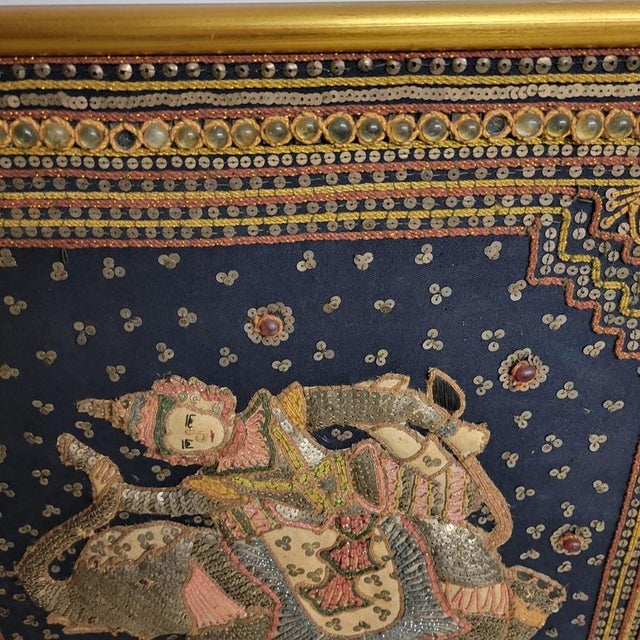 A richly embellished Burmese Kalaga tapestry featuring an elaborately costumed figure riding a ceremonial elephant,...