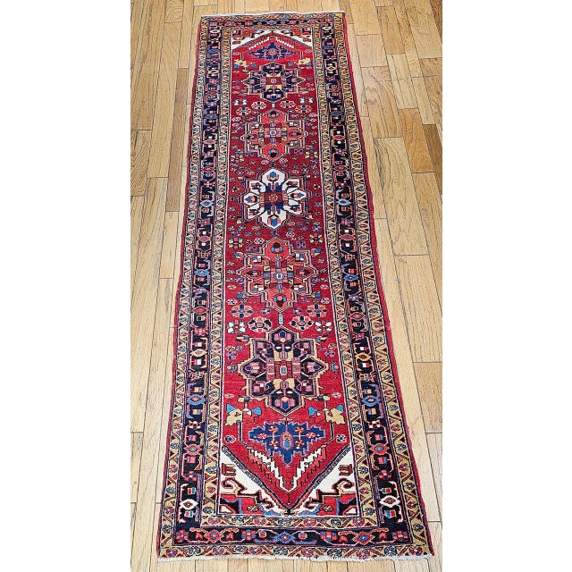 "This vibrant vintage Persian Heriz runner features a striking geometric composition with five axial medallions rendered...