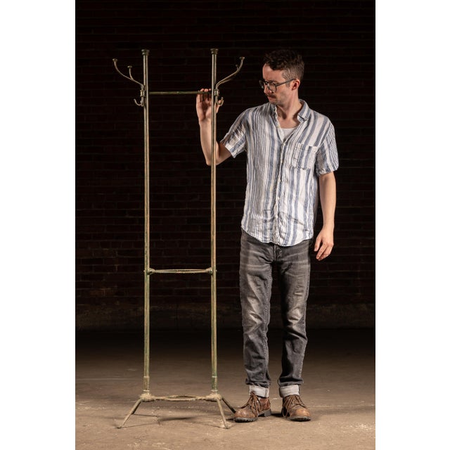 Description: Freestanding industrial metal hall tree constructed from tubular steel with paired uprights, splayed four-leg...