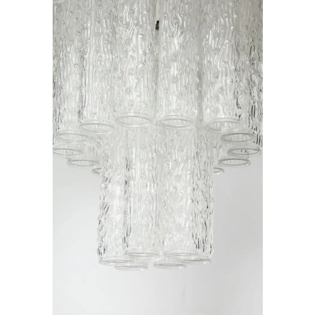 A three-tier chandelier handcrafted in Italy. The piece is made up of a metal frame that supports three tiers of round,...