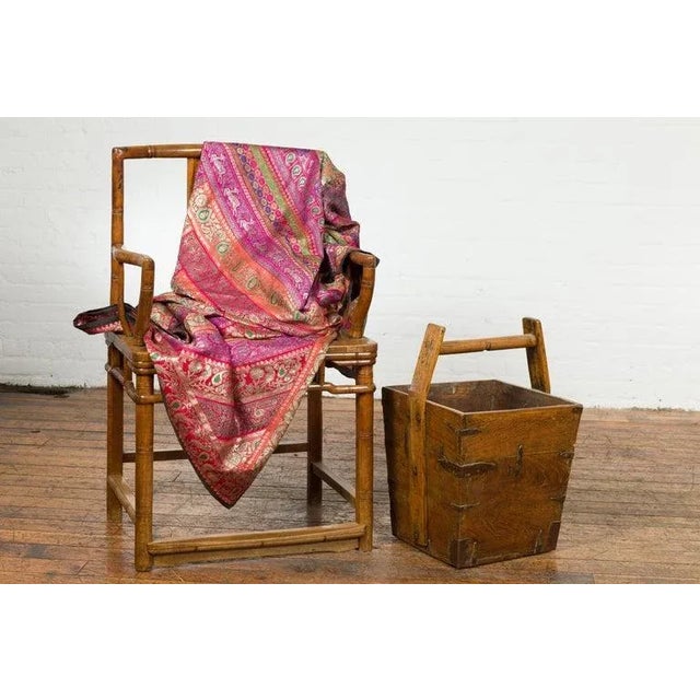 A rustic Chinese Qing Dynasty period wooden grain basket from the 19th century, with large carrying handle and metal...