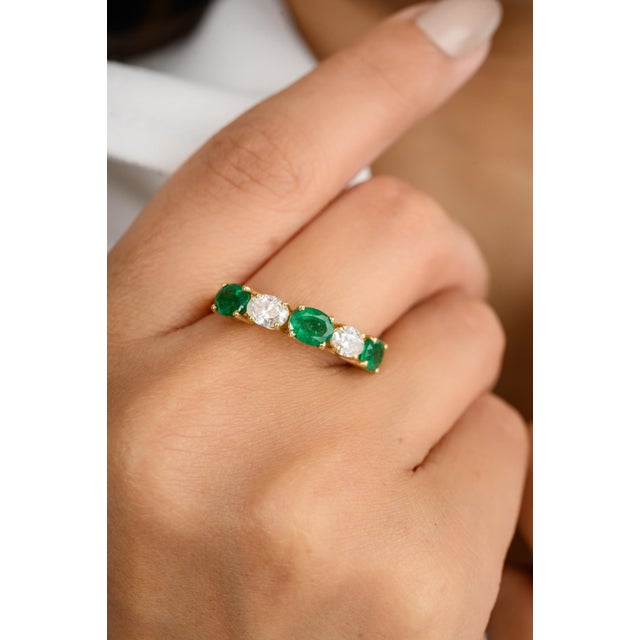 This modern alternative wedding band showcases an oval-cut emerald and diamond set east-west in 18K yellow gold. The...