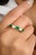 This modern alternative wedding band showcases an oval-cut emerald and diamond set east-west in 18K yellow gold. The...