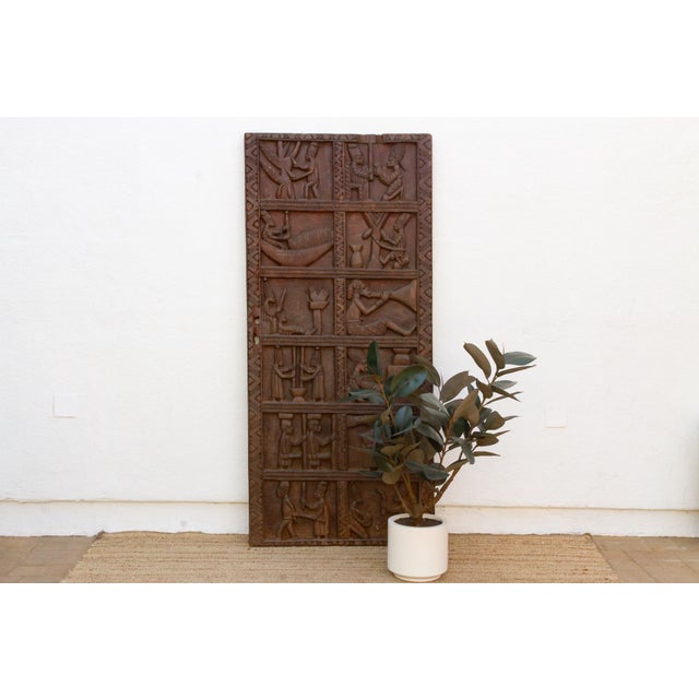 This antique Yoruba door from Nigeria is carved across a single wide plank, divided into four stacked narrative registers,...