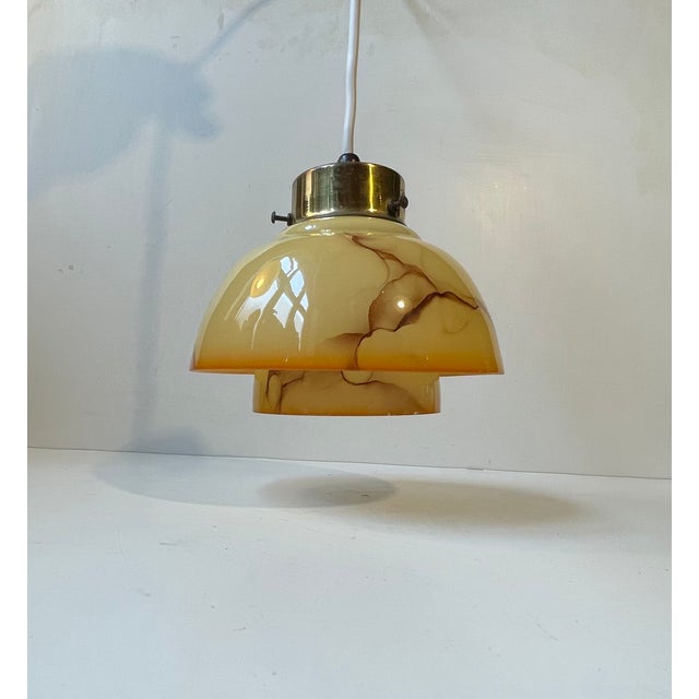 Elegant hanging pendant light composed of pastel/brown orange opaline glass shades decorated with marble effects. It...