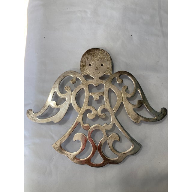 This vintage pair of silverplate angel trivets features pierced scrollwork bodies, smiling faces, and outstretched wings....