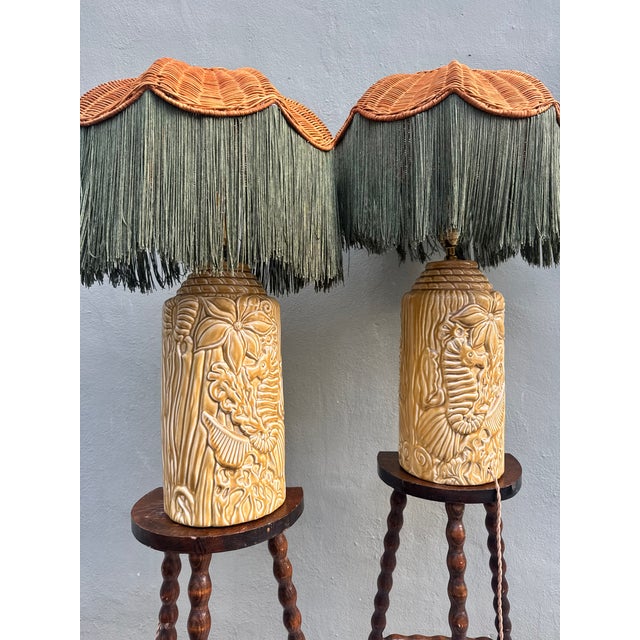 An extraordinary pair of vintage ceramic table lamps: cylindrical cream and amber bases covered in raised relief depicting...