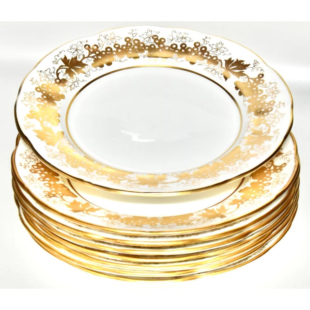 Eight glamorous white and gold midcentury English bone china porcelain plates having scalloped rims, moulded embossed...