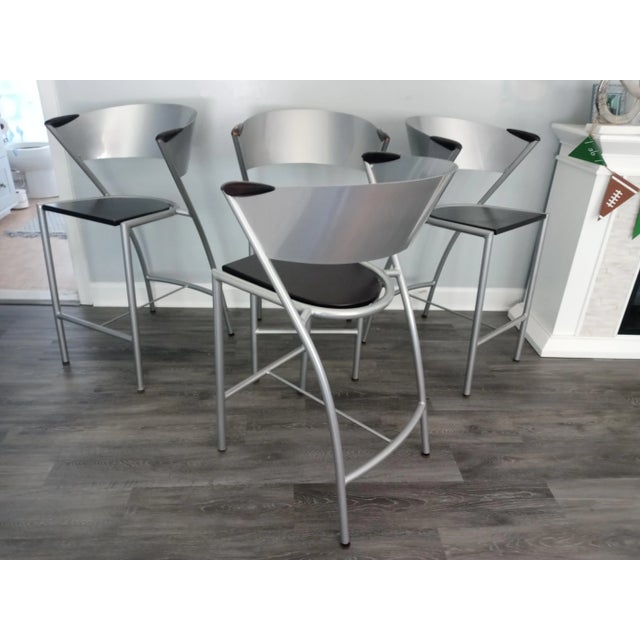 Stunning vintage modern bar stools. A retro style curved metal backrest and frame. Black wood seats and wood armrests. One...