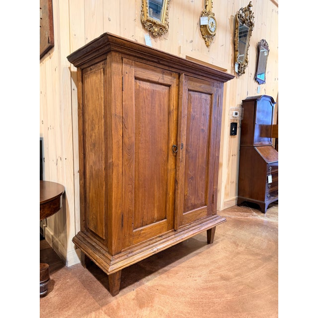 This is a beautiful antique pine armoire cabinet showcasing a classic paneled façade and a rich, naturally aged finish...