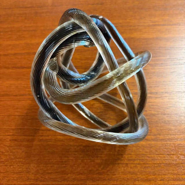 An intriguing vintage art glass sculpture featuring an elegant open knot form crafted from a continuous ribbed glass...