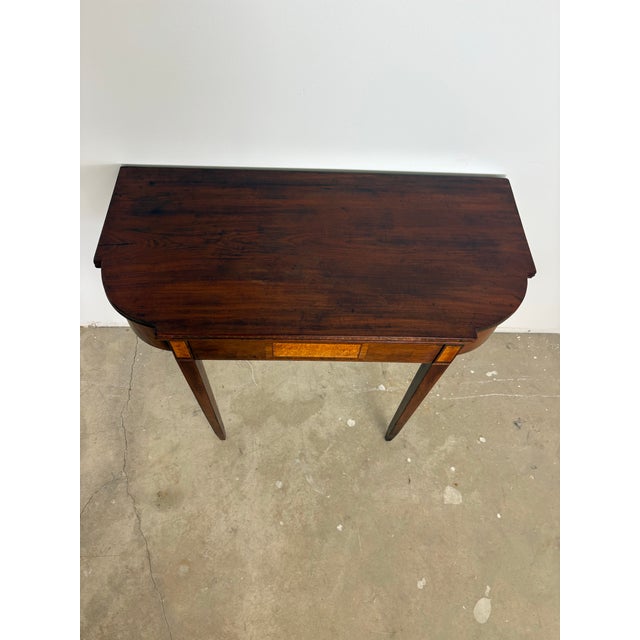 A finely proportioned George III mahogany fold-over demi lune / card table, dating to circa 1800, distinguished by elegant...
