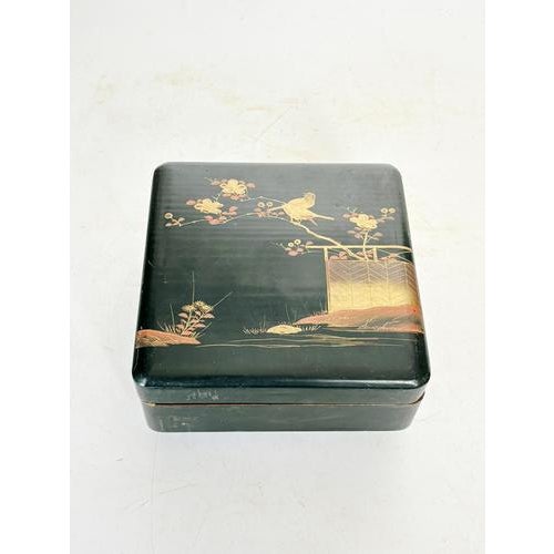 An elegant antique Japanese box in black lacquered wood, decorated with a delicate gold motif depicting a bird perched on...