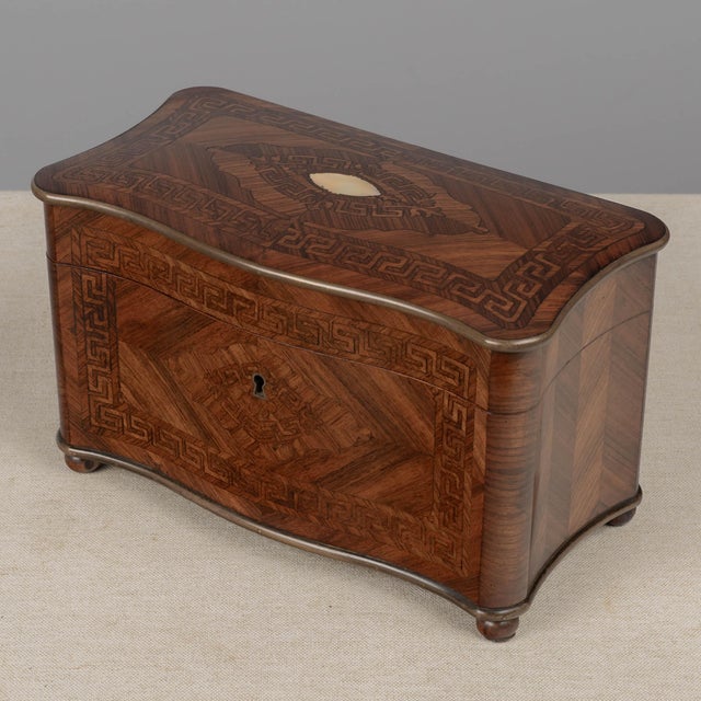 A 19th century French Napoleon III marquetry double compartment tea caddy, featuring a serpentine silhouette and parquetry...