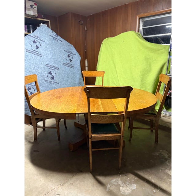 A lovely early 20th-century oak dining set featuring a round pedestal table and four matching chairs in classic Arts &...