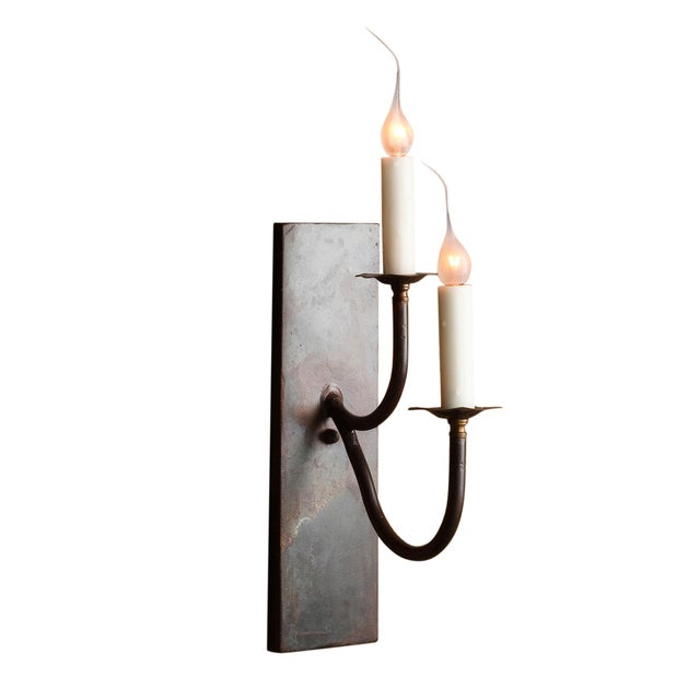 Two slender steel forms stacked vertically  the pair reads as a graphic mark on the wall rather than a pair of fixtures....