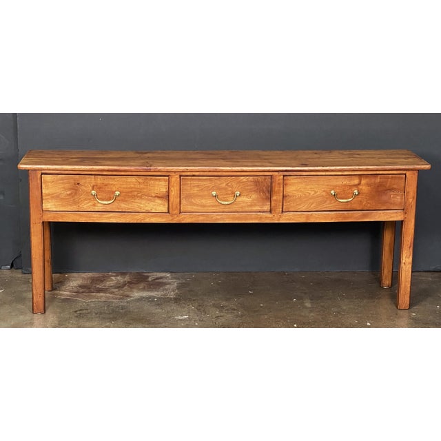 A fine French console sideboard (or serving table) of patinated cherrywood, featuring a rectangular plank top over a...