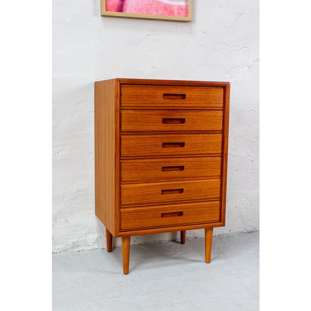 This teak chest of drawers combines ample storage space with a compact, balanced design. The warm wood tone and subtle...