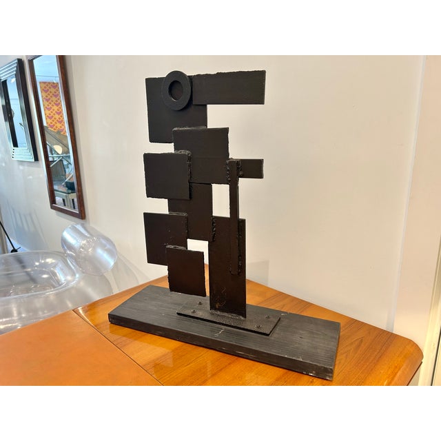 Geometric, abstract sculpture in welded, blackened iron on a solid wood base. Approximately 45 pounds. Wooden Base...