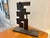 Geometric, abstract sculpture in welded, blackened iron on a solid wood base. Approximately 45 pounds. Wooden Base...
