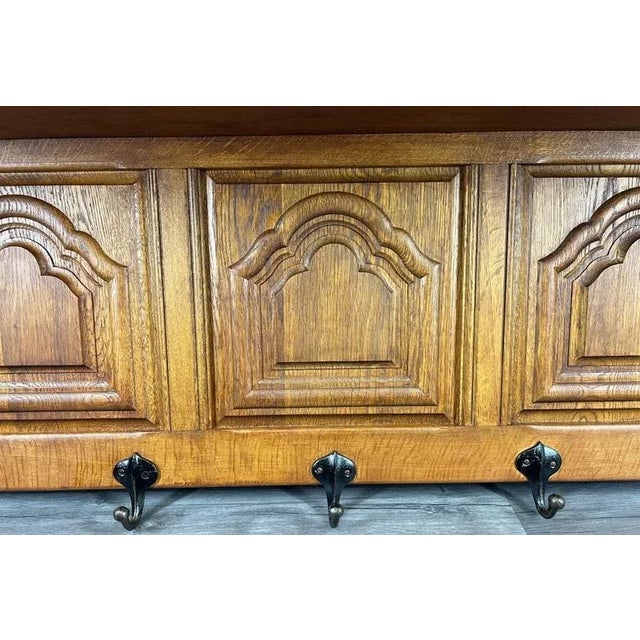 A beautifully crafted Vintage French oak wall shelf featuring five sturdy metal hooks and elegant carved detailing. This...