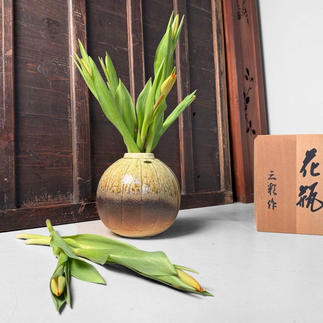 This distinctive ikebana vase features a compact, well-balanced spherical form with a subtly recessed opening. Its...