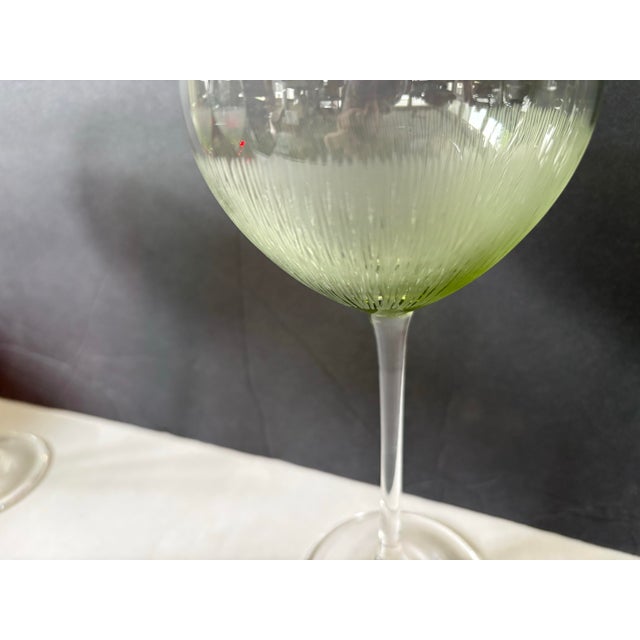 These sculptural stemware pieces showcase a soft transition from clear to olive green, enhanced by vertical optic ribbing...